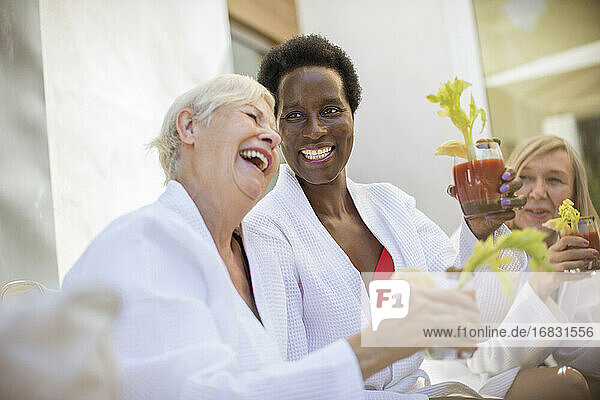 Happy senior women friends enjoying bloody mary cocktails