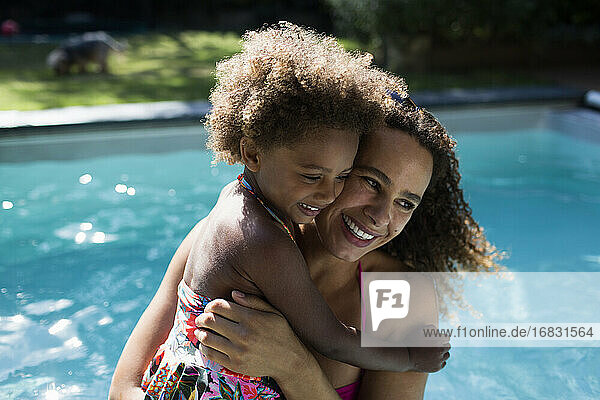 Glückliche Mutter und Tochter umarmen bei sonnigen Sommer poolside