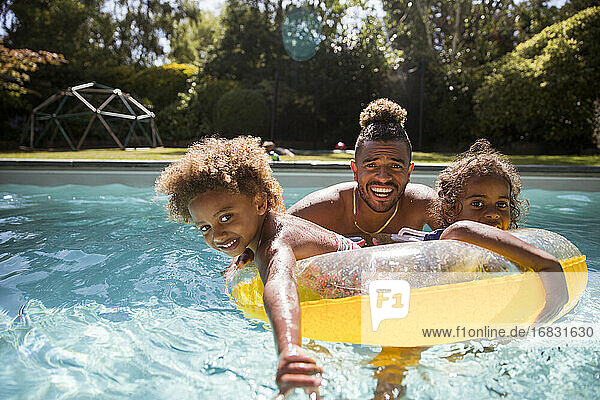 Porträt glücklich Vater und Töchter spielen in sonnigen Schwimmbad