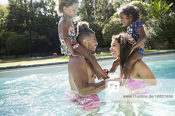 Playful Eltern spielen Huhn mit Töchter auf den Schultern im Pool