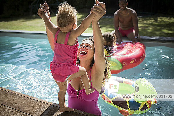 Playful Mutter Heben Kleinkind Tochter in sonnigen Schwimmbad