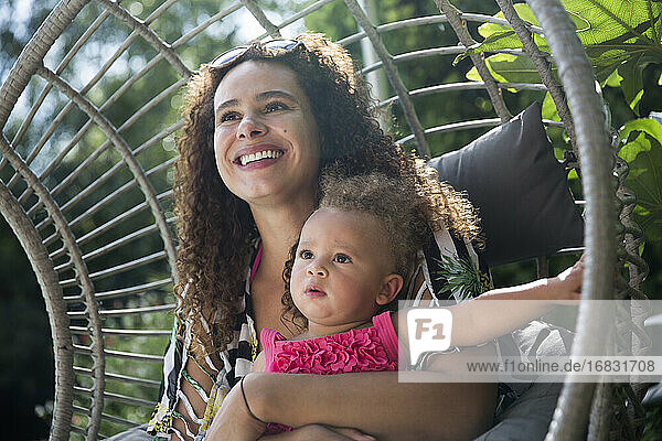 Glückliche Mutter hält Tochter auf sonnigen Terrasse