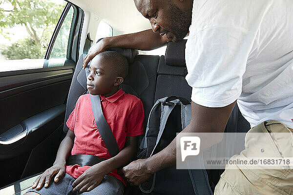 Vater Befestigung Sicherheitsgurt für Sohn auf dem Rücksitz des Autos