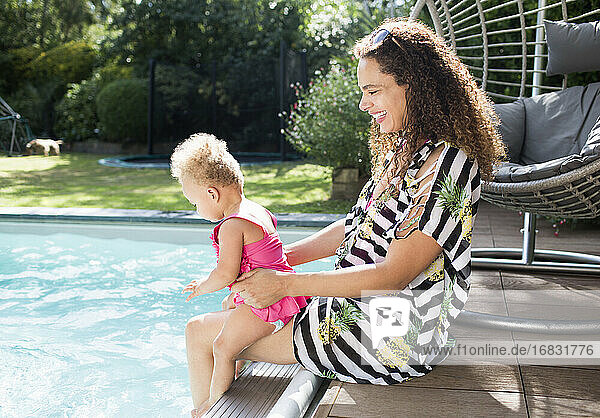 Happy mother and toddler daughter at sunny summer poolside