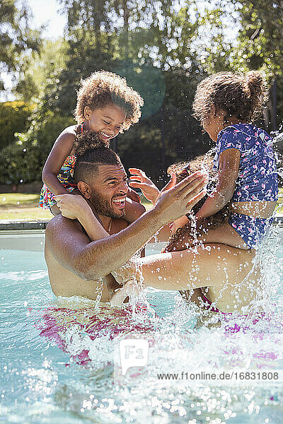 Playful Eltern und Töchter spielen Huhn in sonnigen Schwimmbad