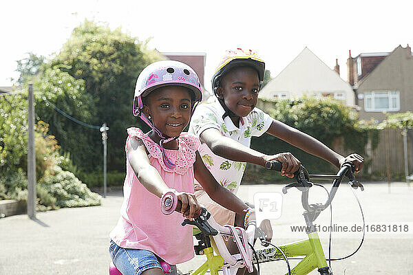 Porträt glücklich Bruder und Schwester Reiten Fahrräder in sonnigen Nachbarschaft