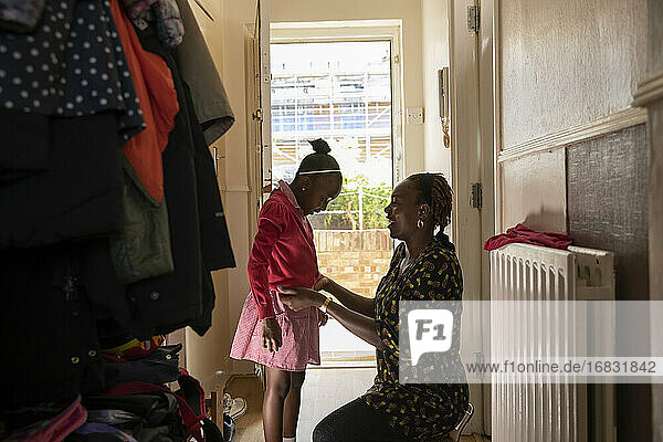 Mutter hilft Tochter mit Jacke an Haustür