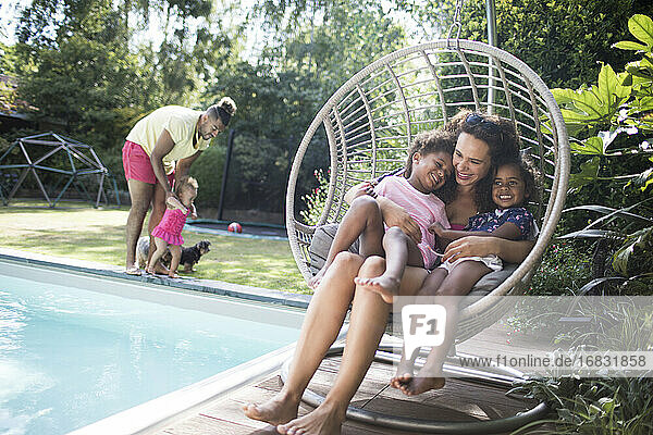 Glückliche Mutter und Töchter kuscheln im Sommer Patio Schaukel Stuhl