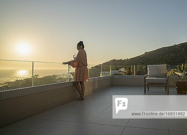 Frau genießt malerischen Sonnenuntergang Meerblick auf Luxus-Terrasse