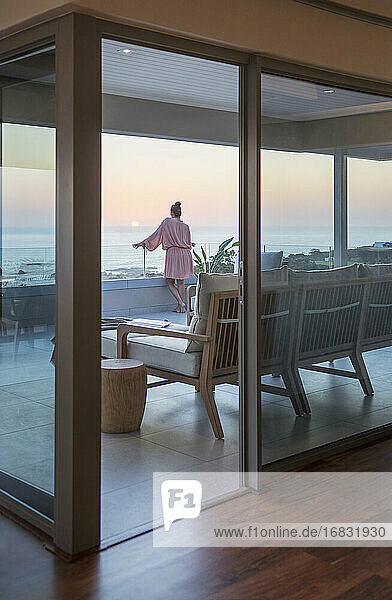 Frau genießt malerischen Sonnenuntergang Meerblick von Luxus-Balkon