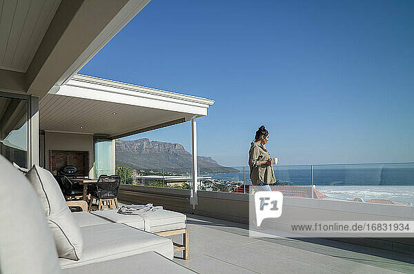 Frau genießt Kaffee auf sonnigen Luxus Balkon mit Meerblick