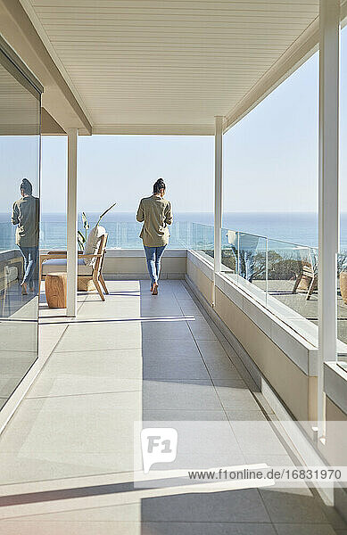 Frau auf sonnigen Luxus Haus Showcase Balkon mit Meerblick