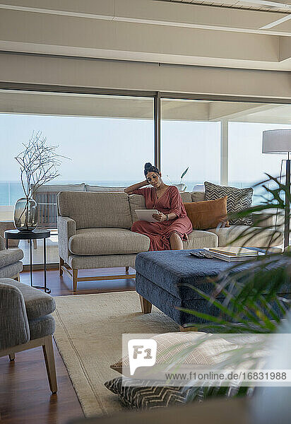 Frau entspannt mit digitalem Tablet auf Sofa in Luxus-Wohnzimmer