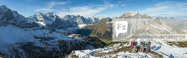 Drei Wanderer auf Wanderweg mit Schnee im Herbst  Wanderung zum Gipfel des Hahnenkampl  Ausblick auf schneebedeckte Gipfel Laliderspitze  Dreizinkenspitze und Spritzkarspitze  hinten Gamsjoch und Gramaijoch  Engtal  Karwendel  Tirol  Österreich  Europa