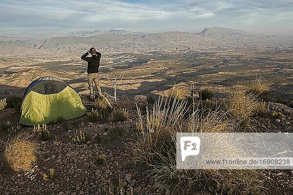 Mann betrachtet die Landschaft des Berges Jbel Bou Naceur auf einem Campingplatz  gesehen von einer Hochebene in der Nähe der Region Fez-Mequinez  Provinz Sefru  Mittlerer Atlas  Marokko  Afrika