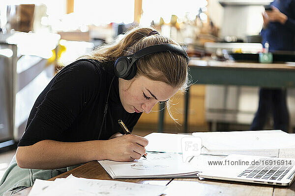teenage girl wearing headphones  drawing on paper