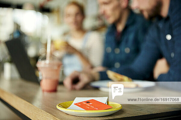 Menschen an einem Cafe-Tisch  eine Untertasse mit Kassenbon und Kreditkarte.