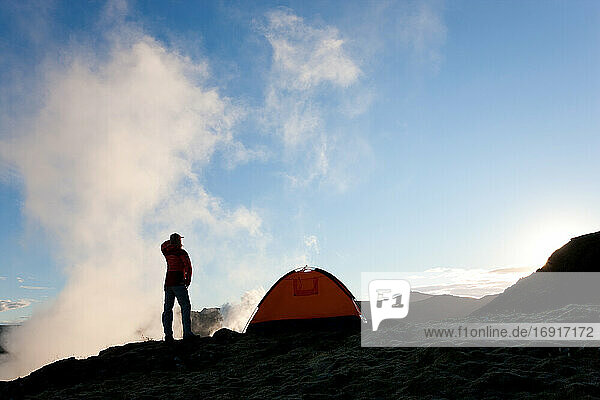 Woman standing by tent at sunrise  Iceland