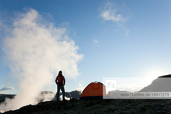 Woman standing by tent at sunrise  Iceland
