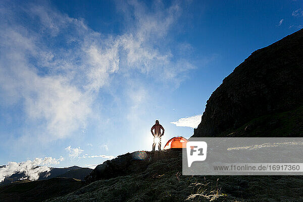 Frau stehend am Zelt bei Sonnenaufgang  Island