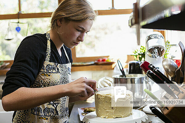 Teenager-Mädchen in der Küche Anwendung Zuckerguss auf Kuchen