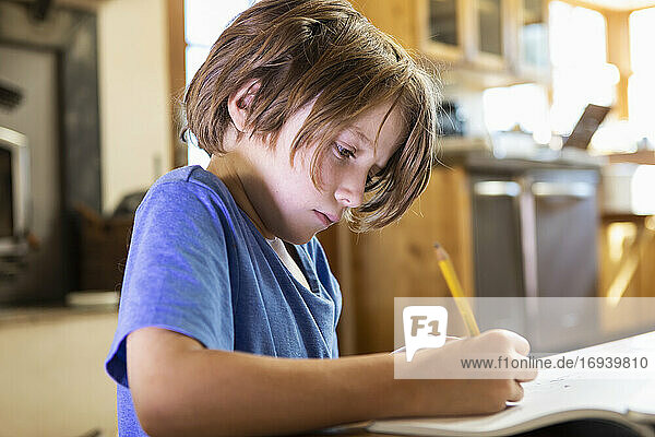 Junger Junge zu Hause schreiben und zeichnen in seinem Zeichenblock