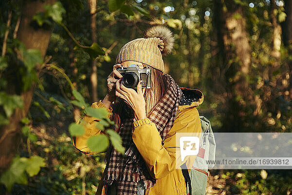 Frau beim Fotografieren mit Kamera im Wald