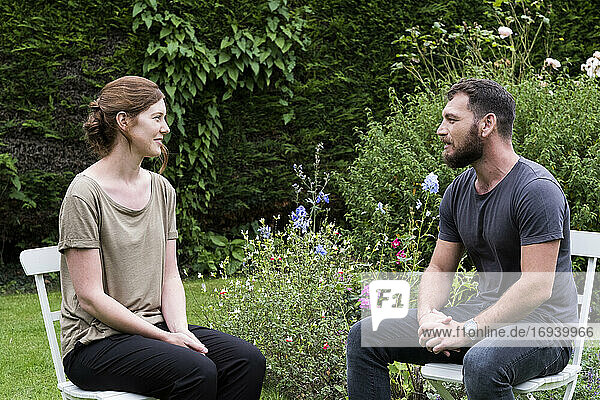Mann und ein Therapeut sitzen in einem Garten und unterhalten sich.