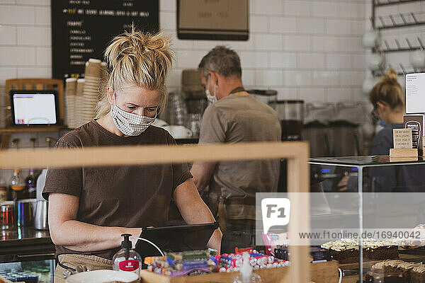 Waitress wearing face mask working in a cafe.