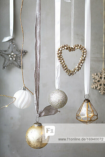 Weihnachtsschmuck  Nahaufnahme von silbernen  weißen und goldenen Weihnachtskugeln auf Bändern auf grauem Hintergrund.