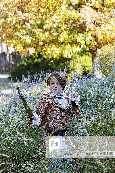 Junger Junge als Pirat gekleidet  der eine lange Pistole hält.