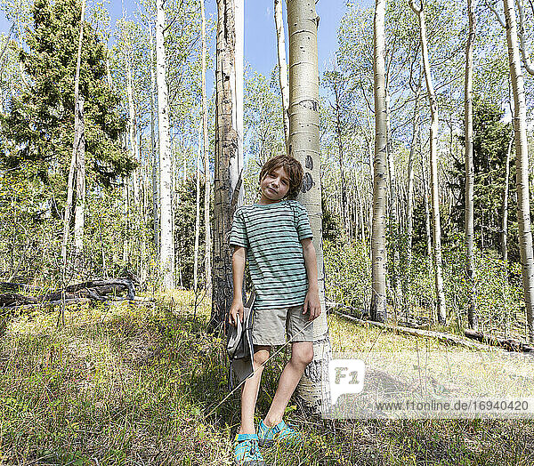 Portrait of 7 year old boy standing in forest of Aspen trees