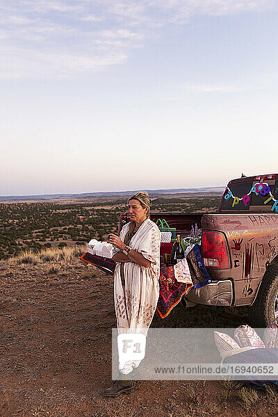 Erwachsene Frau lehnt an Pickup-Truck bei Sonnenuntergang  Galisteo Basin