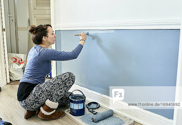 Frau malt Wand zu Hause.