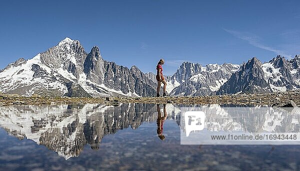 Young woman walking in front of mountain panorama  reflection in Lac Blanc  mountain peaks  Grandes Jorasses and Mont Blanc massif  Chamonix-Mont-Blanc  Haute-Savoie  France  Europe