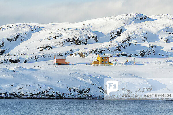 Isolierte Holzhäuser im Schnee entlang des Fjords im arktischen Winter  Oksfjord  Troms og Finnmark  Nordnorwegen  Skandinavien  Europa