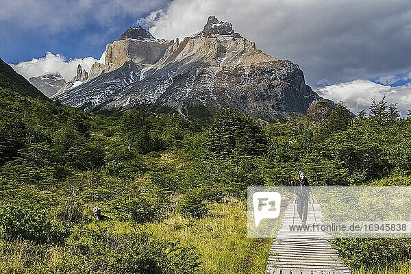 Woman hiking in Torres del Paine National Park with Los Cuernos and the Paine Massif behind  Patagonia  Chile