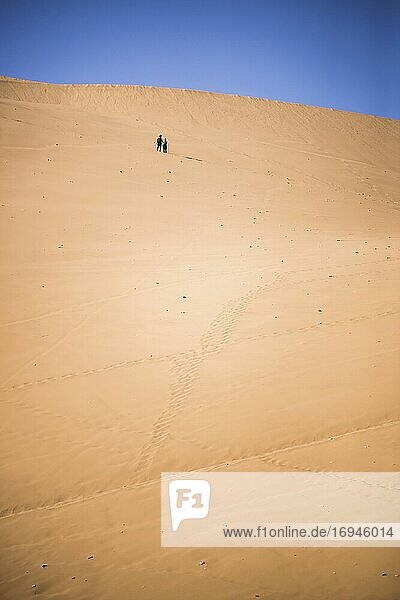Couple climbing sand dunes at Huacachina  a village in the desert  Ica Region  Peru