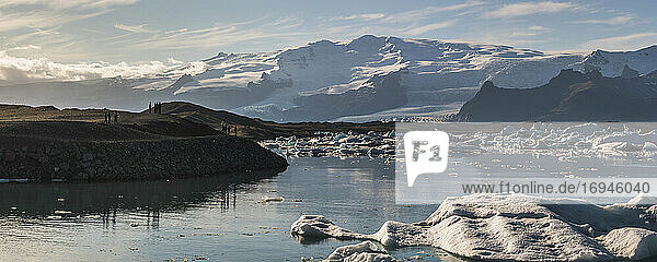 Touristen an der Gletscherlagune Jokulsarlon bei Sonnenuntergang  Südostisland