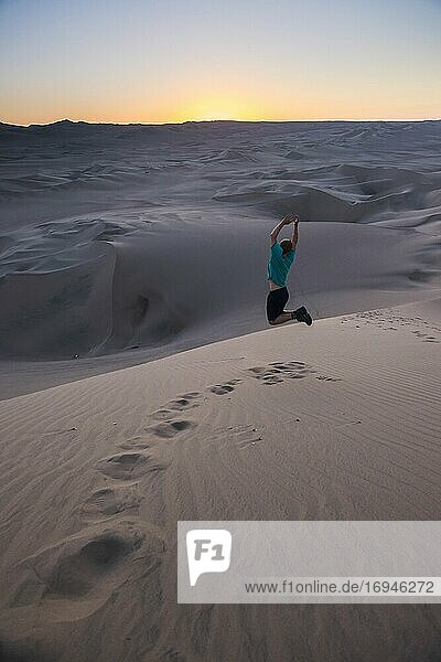Tourist jumping in the desert at sunset at Huacachina  Ica Region  Peru