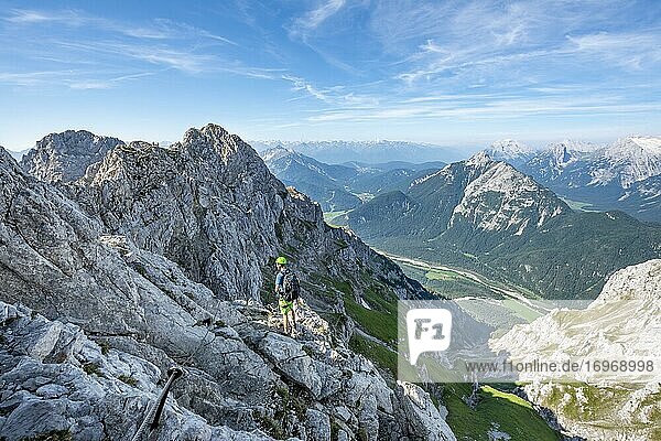 Mountaineer climbs on a secured fixed rope route  Mittenwalder Höhenweg  view into the Isar valley near Mittenwald  Karwendel Mountains  Mittenwald  Bavaria  Germany  Europe
