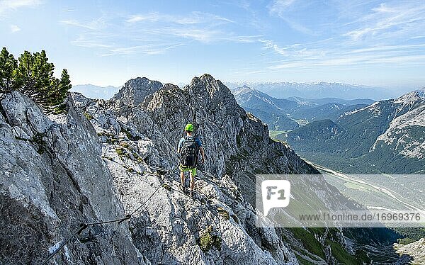 Bergsteiger klettert an einem gesicherten Klettersteig  Mittenwalder Höhenweg  Ausblick ins Isartal bei Mittenwald  Karwendelgebirge  Mittenwald  Bayern  Deutschland  Europa