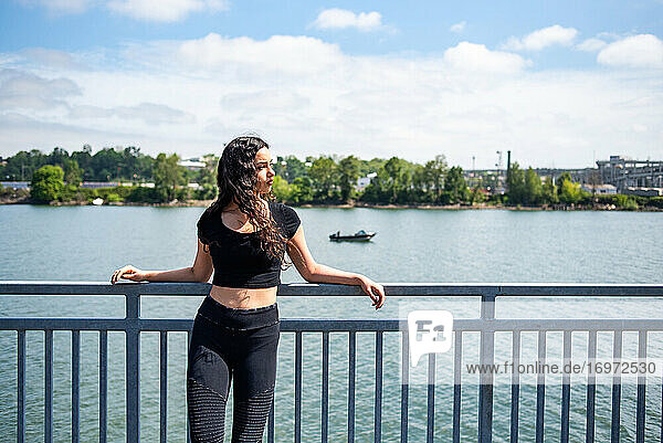 Junge Frau lehnt an einem Geländer mit Fluss und Boot im Hintergrund