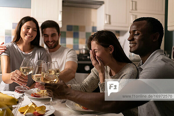 Young woman laughing while drinking wine with friends and black boyfriend