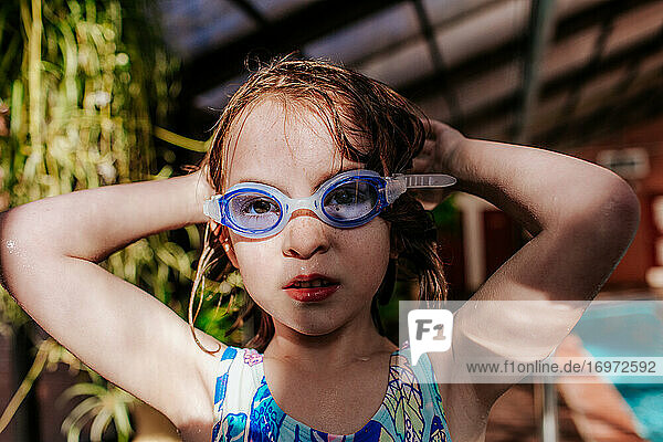 Junges Mädchen setzt Schwimmbrille im Schwimmbad auf