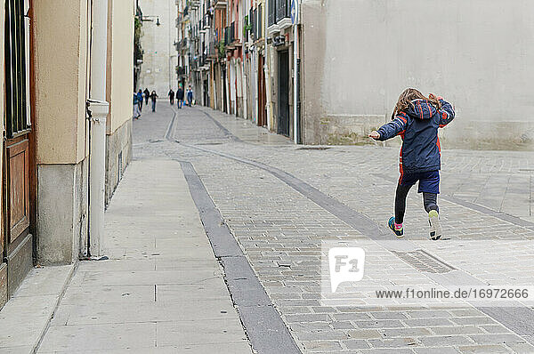 Girl jumping on a walk in the middle of a street in the old town