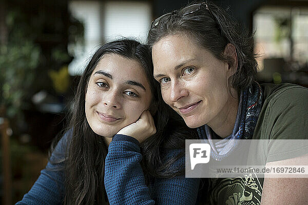Close-up of mothe and pretty teen daughter smiling at camera in