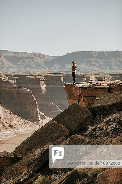 Frau steht am Rand einer hohen Klippe und blickt über die Wüste  Hite  Utah