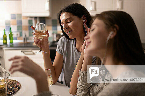 Junge Frau genießt Wein und Musik bei einem Freund