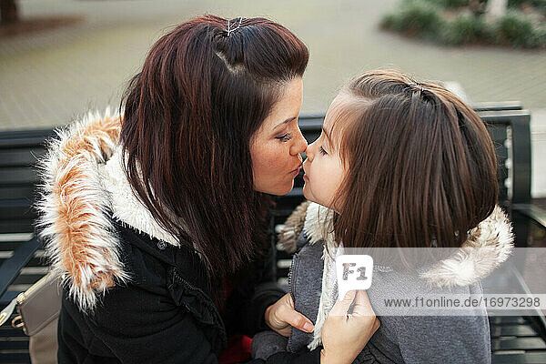 Mother kissing her daugher in the park